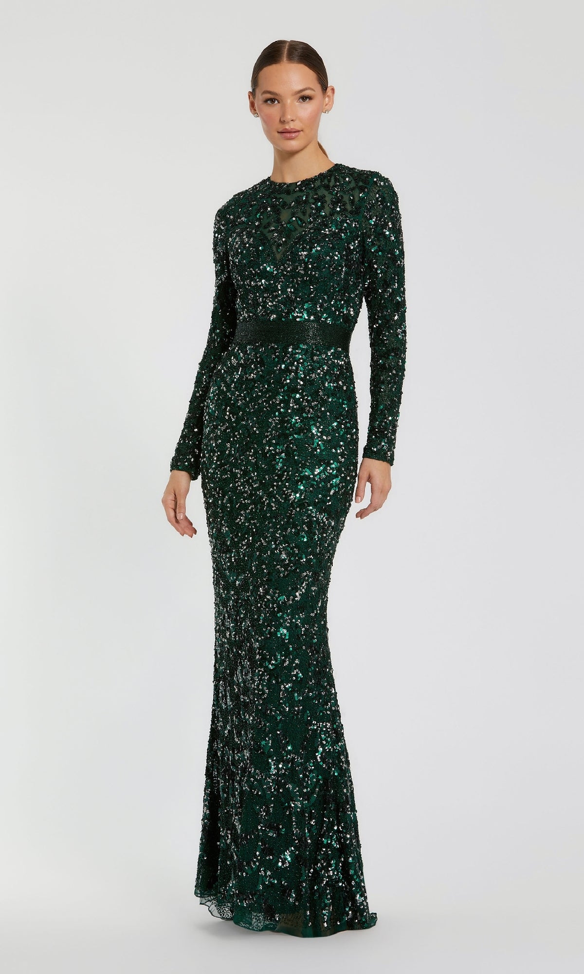 A woman wears the Mac Duggal 5453 long sleeve sequin formal dress, featuring a fitted silhouette in green, styled as an elegant evening gown against a simple light background.